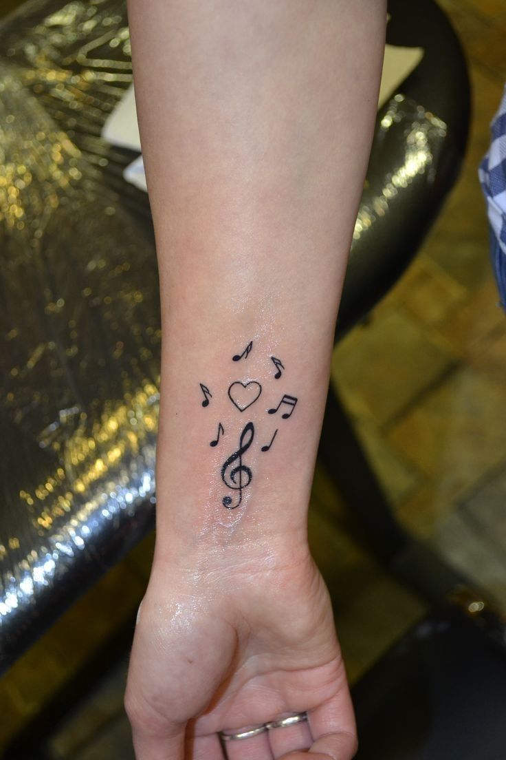 Hình xăm nốt nhạc và trái tim nhỏ trên cổ tay, phong cách blackwork, chi tiết rõ nét, ảnh độ phân giải HD.