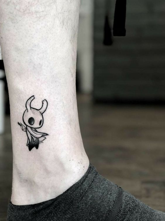 Hình xăm đen trắng mini ở cổ chân Hình xăm nhân vật hoạt hình mini trên chân, phong cách blackwork, chi tiết rõ nét, ảnh HD.