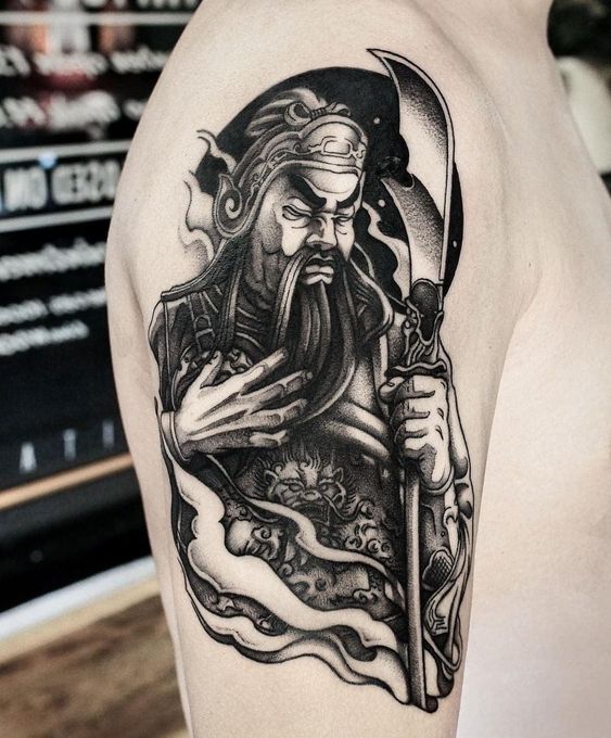 Hình xăm Quan Vũ ở bắp tay Hình xăm chiến binh cổ điển trên bắp tay, phong cách blackwork, chi tiết rõ nét, độ phân giải cao.