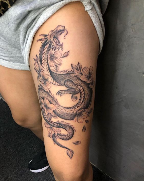 Hình xăm rồng blackwork trên đùi, kết hợp hoa, chi tiết rõ nét, ảnh HD.