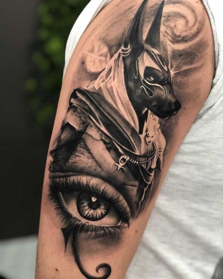 Hình xăm Anubis và mắt trên bắp tay, phong cách blackwork chi tiết, ảnh HD.