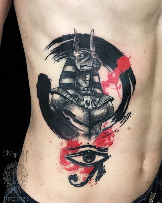 Hình xăm Anubis phong cách blackwork trên sườn, chi tiết cao, kết hợp màu đỏ, độ phân giải HD.
