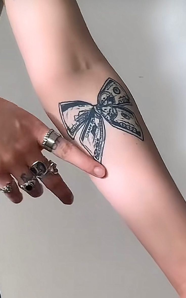 Hình xăm tôn lên vẻ đẹp quý phái Hình xăm nơ trên cánh tay, phong cách blackwork, chi tiết rõ nét, độ phân giải HD.