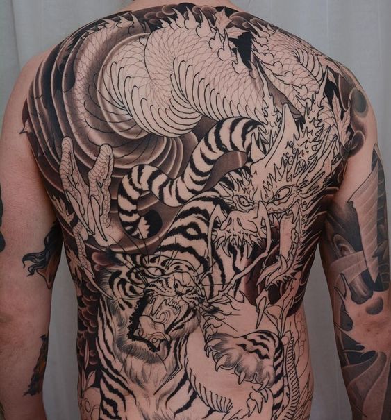 hoàn thiện hình xăm long tranh hổ đấu Hình xăm rồng và hổ, phong cách blackwork, chi tiết trên lưng, ảnh HD sắc nét.