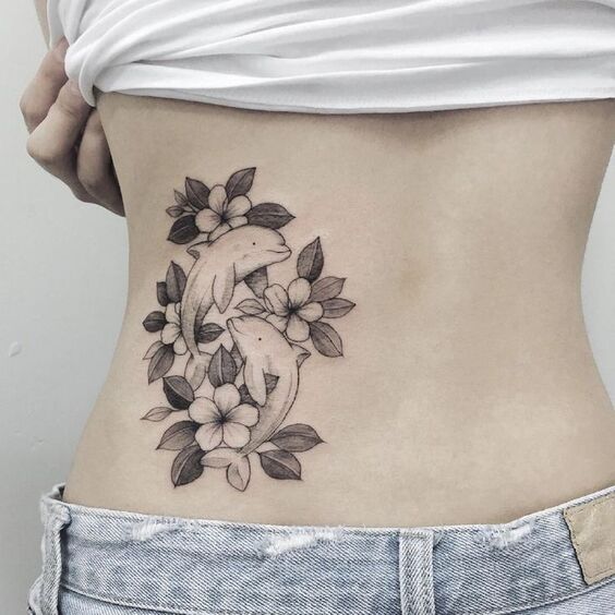 Xăm cá heo kết hợp cùng bông hoa Hình xăm cá heo và hoa trên eo, phong cách blackwork, chi tiết rõ nét, ảnh HD.