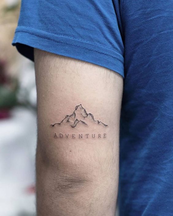 Hình xăm núi trên bắp tay phong cách blackwork chi tiết, chữ "Adventure", ảnh HD.