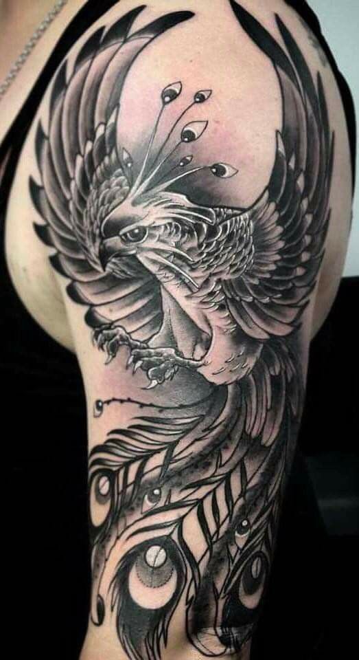 Khách xăm hình phượng hoàng đơn sắc Hình xăm chim phượng hoàng trên cánh tay, phong cách blackwork chi tiết, ảnh độ phân giải cao.