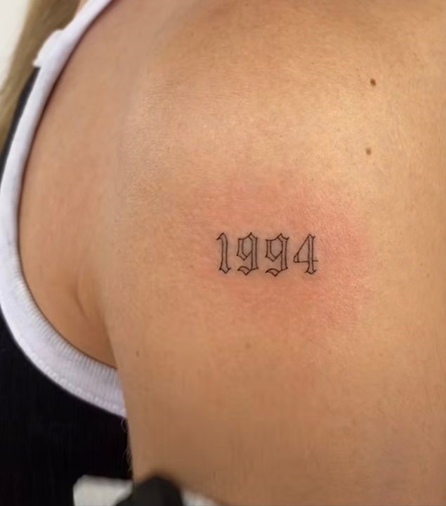 Tattoo bắp tay cho bạn nữ với năm sinh Hình xăm số năm "1994" trên vai, phong cách blackwork, độ chi tiết cao, hình ảnh HD.