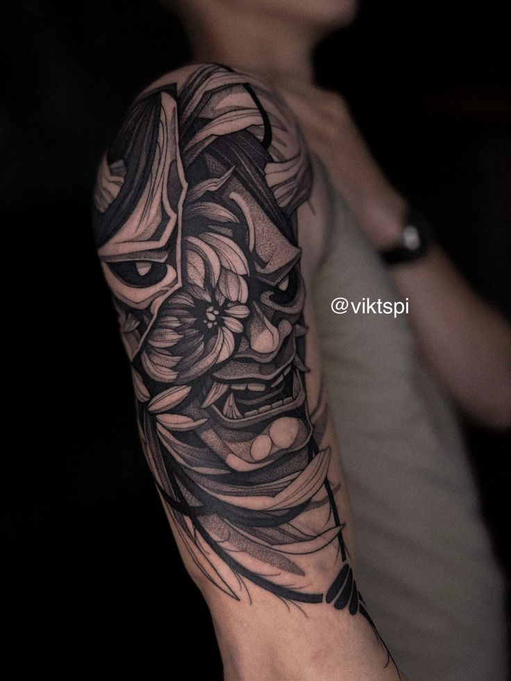 Hình xăm mặt nạ oni phong cách blackwork trên bắp tay, chi tiết sắc nét, ảnh HD.