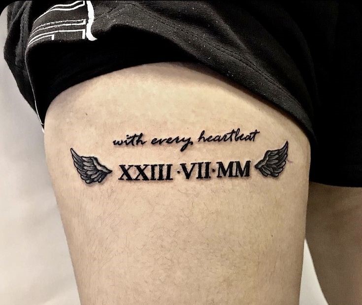 hình xăm chữ số La Mã ở đùi Hình xăm chữ La Mã và cánh trên đùi, phong cách blackwork, độ chi tiết cao, ảnh HD.