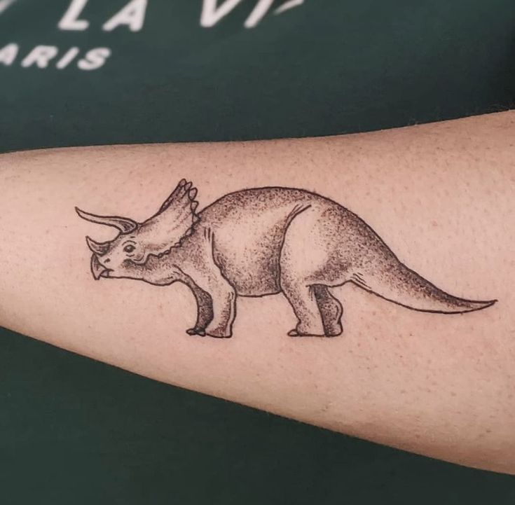 Hình xăm khủng long Triceratops trên cánh tay, phong cách blackwork chi tiết, ảnh HD.
