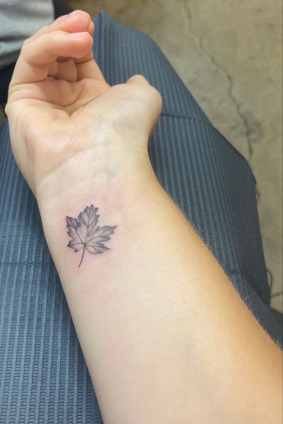 kiểu xăm lá phong nhỏ xíu trên cổ tay Hình xăm lá phong mini trên cổ tay, phong cách blackwork, chi tiết tinh xảo, ảnh chất lượng HD.