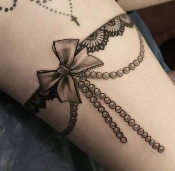 Hình xăm nơ ở đùi, mẫu thứ 8 Hình xăm nơ và ren trên đùi, phong cách blackwork, chi tiết rõ nét, độ phân giải HD.
