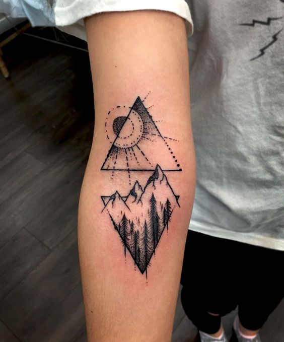 Hình xăm phong cảnh núi và mặt trời tối giản trên cánh tay, phong cách blackwork, chi tiết rõ nét.