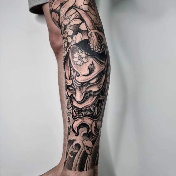 Hình xăm mặt nạ Oni phong cách blackwork trên chân, chi tiết tinh xảo, ảnh HD.