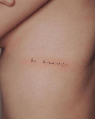 Hình xăm chữ "be brave" trên sườn, phong cách minimalist, ảnh HD chi tiết.