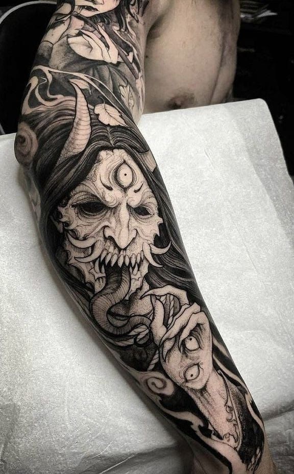 Hình xăm mặt quỷ phong cách blackwork trên cánh tay, chi tiết cao, ảnh HD.