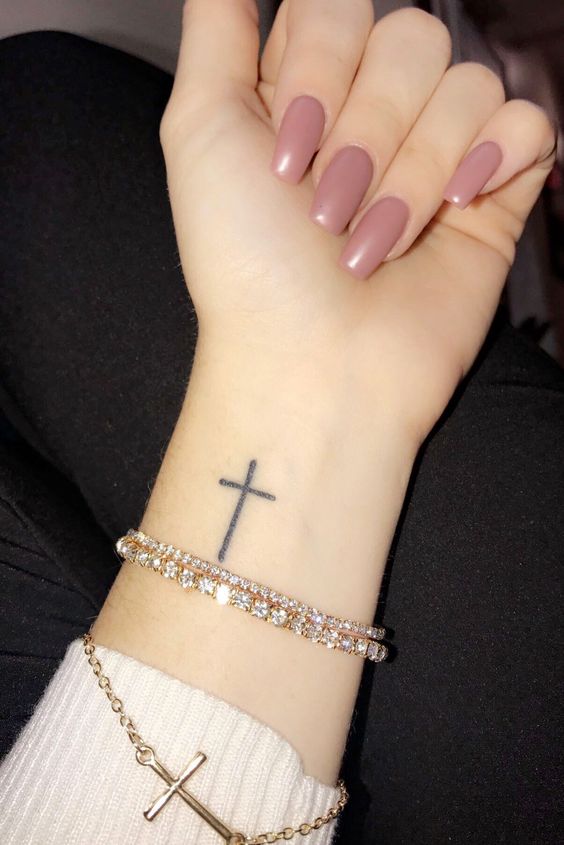 Hình xăm chữ thập mini trên cổ tay, phong cách blackwork, hình ảnh chi tiết rõ nét.