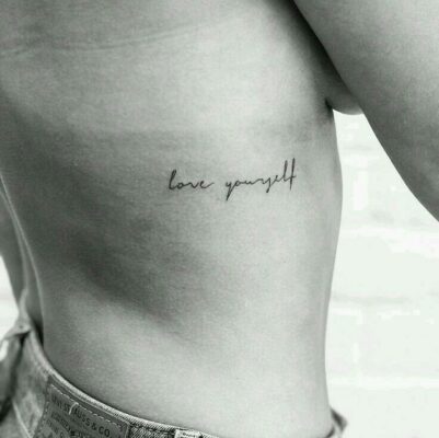 Hình xăm chữ "love yourself" trên sườn, phong cách tối giản, hình xăm đen trắng, ảnh độ phân giải cao.