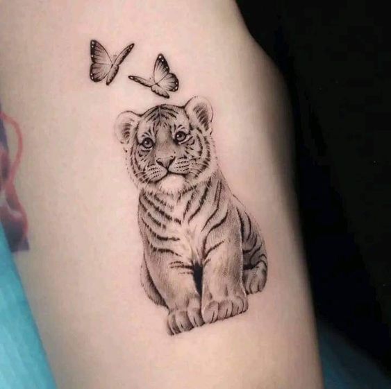 Hình xăm hổ con và bướm trên tay, phong cách blackwork, chi tiết sắc nét, độ phân giải cao.