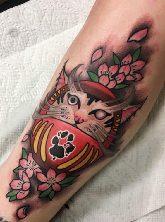 Thiết kế xăm Daruma với mặt mèo thần tài kết hợp hoa anh đào Hình xăm mèo phong cách màu sắc trên bắp tay, họa tiết hoa anh đào, độ chi tiết cao, ảnh HD.