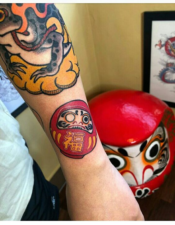 mẫu xăm daruma phổ biến được nhiều khách lựa chọn Hình xăm búp bê Daruma và rồng trên cánh tay, phong cách màu sắc, độ chi tiết cao, ảnh HD.