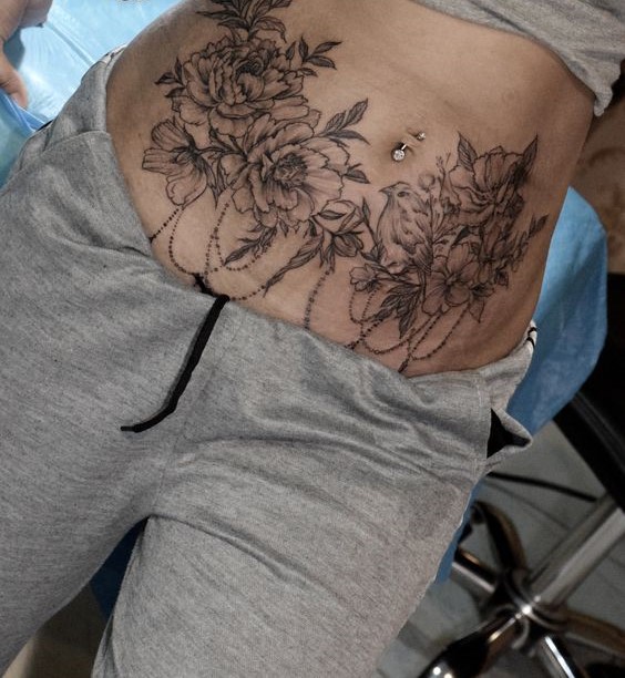 Hình xăm hoa và chim phong cách blackwork trên bụng, chi tiết rõ nét, ảnh HD.