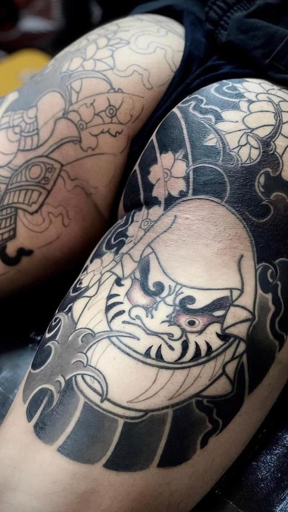 Mẫu xăm Daruma toàn bộ hai bên mông cho khách hàng cá tính Hình xăm mặt nạ Nhật Bản trên đùi, phong cách blackwork, chi tiết sắc nét, độ phân giải HD.