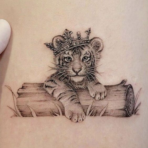 Hình xăm sư tử con đội vương miện, phong cách blackwork chi tiết trên da; độ phân giải HD.