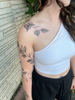 Hình xăm lá trên vai và cánh tay, phong cách blackwork, chi tiết rõ nét, ảnh HD.