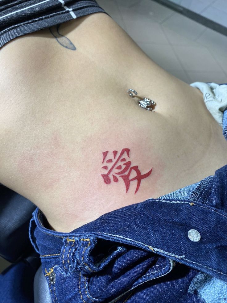 Hình xăm chữ đỏ ở vùng bụng, phong cách đơn giản, ảnh độ phân giải cao.