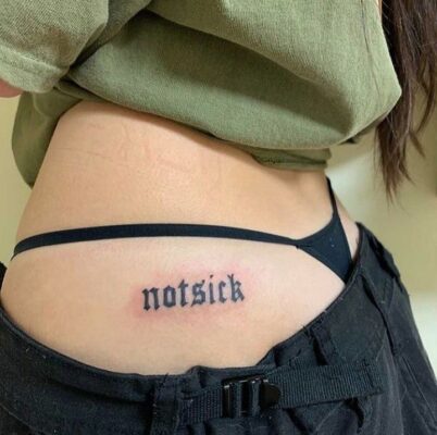 Hình xăm chữ "notsick" ở eo, phong cách blackwork, chi tiết rõ nét, ảnh độ phân giải cao.