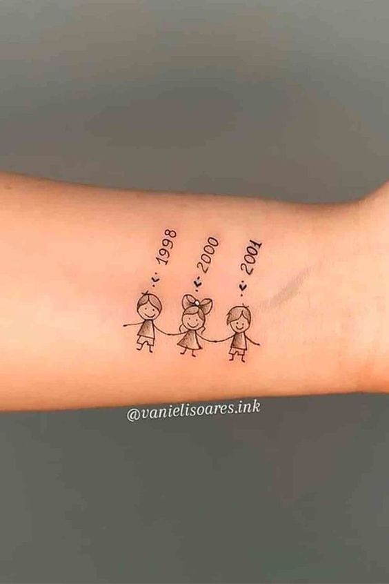 Hình xăm đơn giản trên tay, phong cách nét mảnh, hình ba nhân vật nhỏ và năm sinh, độ phân giải HD.