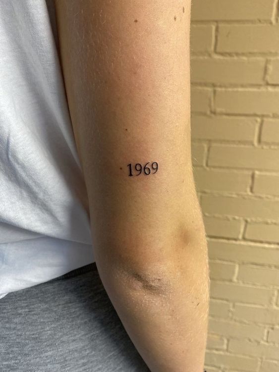 Hình xăm số "1969" trên cánh tay, phong cách tối giản, ảnh chất lượng HD.