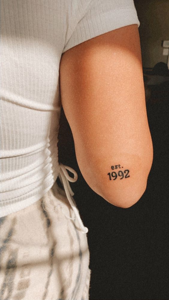 Hình xăm chữ "est. 1992" trên tay, phong cách tối giản, độ phân giải HD.