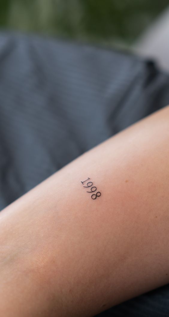 Hình xăm số "1998" trên cánh tay, phong cách minimal, độ phân giải HD.