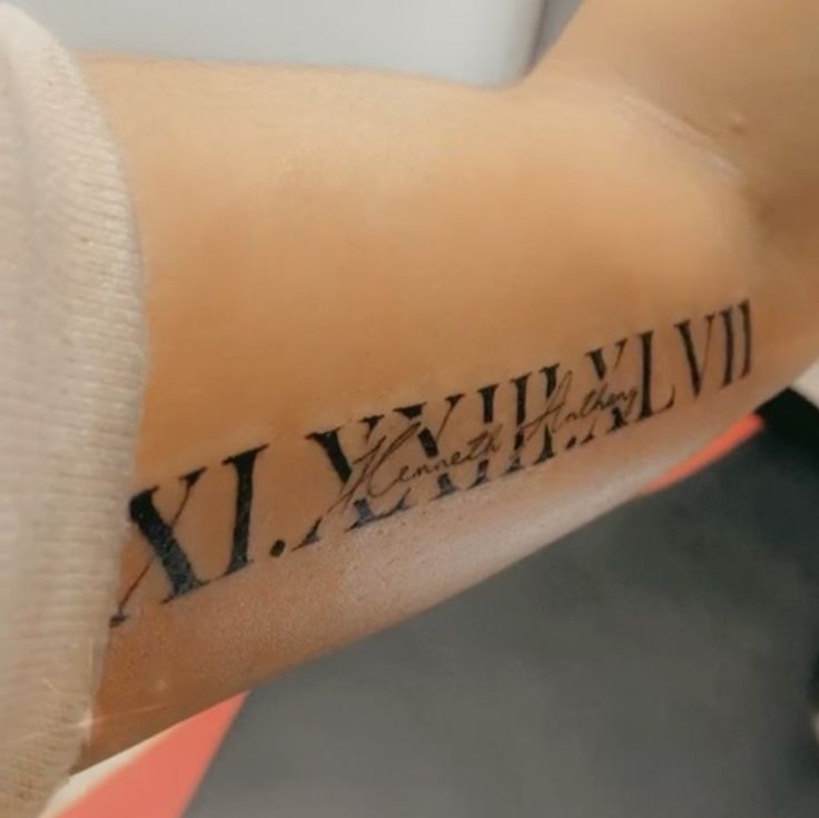 Nghệ thuật tattoo bắp tay mẫu chữ số La Mã Hình xăm chữ số La Mã và chữ viết tay ở cánh tay, phong cách blackwork, chi tiết rõ nét, ảnh HD.