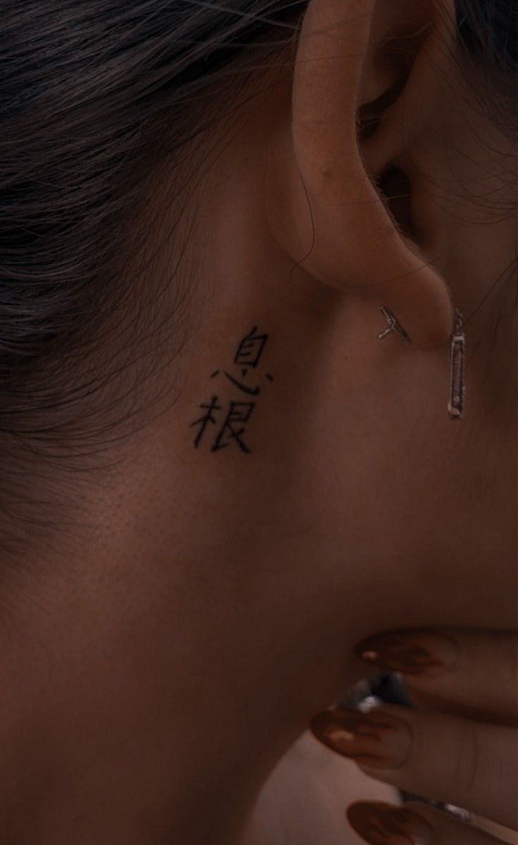 Hình xăm chữ Nhật tinh tế sau tai, phong cách blackwork, chi tiết rõ nét, ảnh HD.