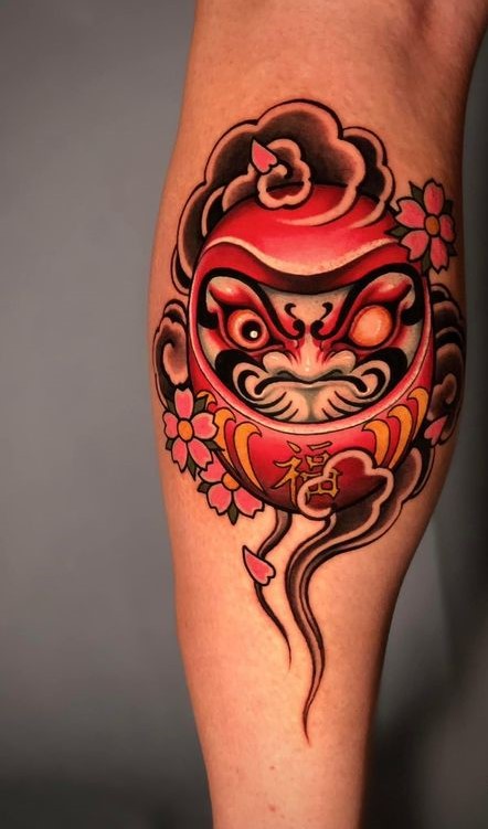 Phong cách xăm hình Daruma độc đáo với gam màu nổi bật Hình xăm Daruma cổ điển trên bắp chân, phong cách màu sắc tươi sáng, chi tiết sắc nét, độ phân giải HD.