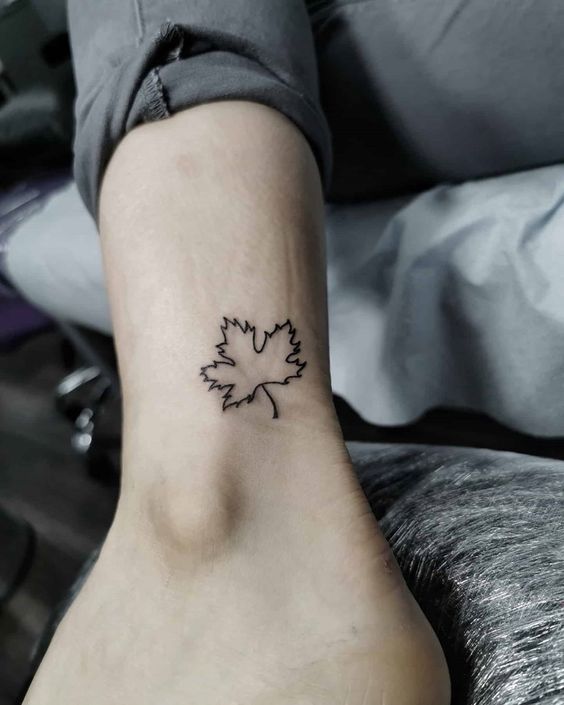 phong cách xăm lá phong tối giản trên cổ chân Hình xăm lá phong mini trên mắt cá chân, phong cách blackwork tối giản, độ phân giải HD.