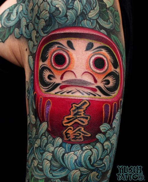 mẫu xăm hình daruma mang ý nghĩa mong cho cuộc sống tốt đẹp Hình xăm búp bê Daruma màu sắc trên cánh tay, phong cách Nhật Bản chi tiết, độ phân giải HD.