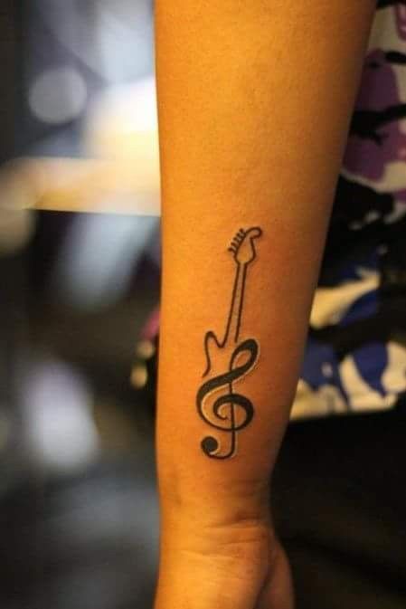 Hình xăm khóa Sol và guitar trên cánh tay, phong cách blackwork, chi tiết rõ nét, độ phân giải HD.