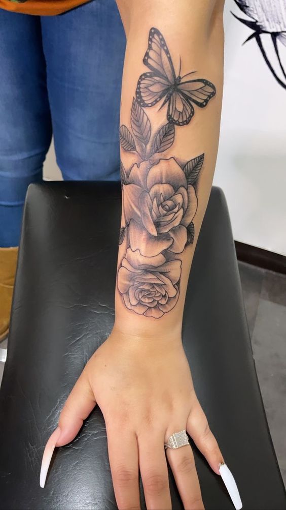 Hình xăm hoa hồng và bướm trên cánh tay, phong cách blackwork, chi tiết rõ nét, ảnh HD.