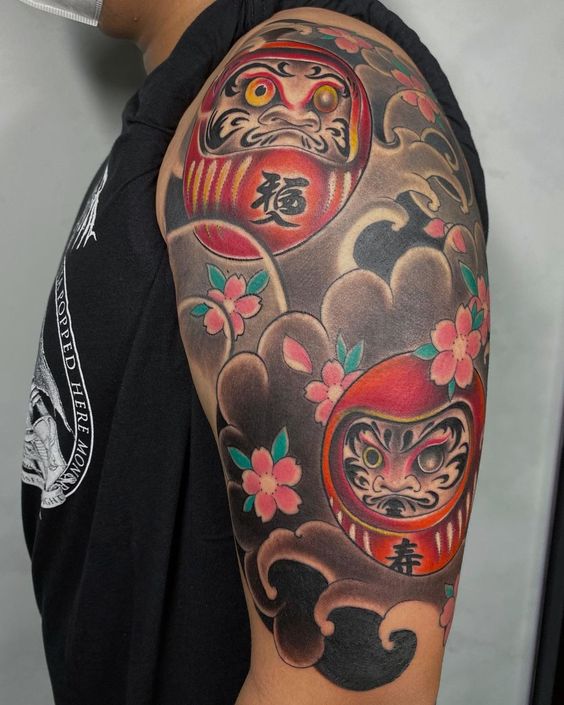 tattoo nhiều mặt daruma cầu may mắn trong cuộc sống Hình xăm Daruma và hoa anh đào trên bắp tay, phong cách truyền thống Nhật Bản, chi tiết sắc nét, ảnh HD.