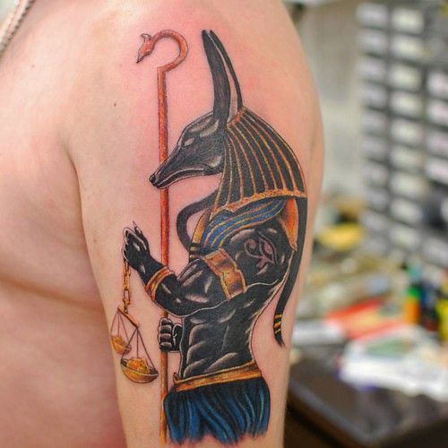 Hình xăm thần Anubis trên bắp tay, phong cách màu sắc chi tiết, độ phân giải HD.