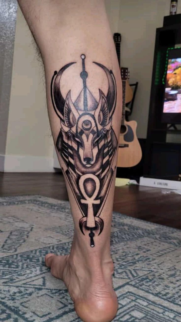 Hình xăm Anubis phong cách blackwork trên bắp chân, chi tiết sắc nét, độ phân giải HD.