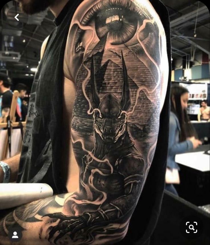 Hình xăm quái vật và kim tự tháp trên cánh tay, phong cách blackwork chi tiết, độ phân giải HD.