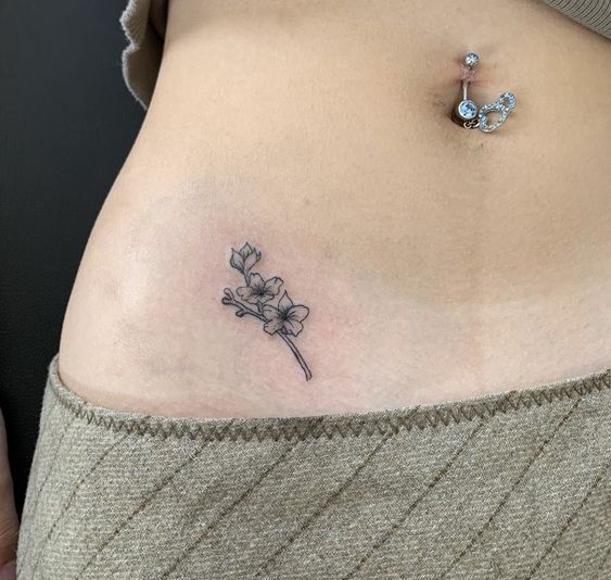 Hình xăm hoa mini trên bụng, phong cách blackwork, chi tiết tinh xảo, ảnh HD.