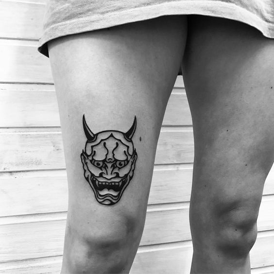 Hình xăm mặt nạ Oni trên đùi, phong cách blackwork, chi tiết rõ nét, ảnh chất lượng HD.