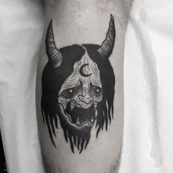 Hình xăm mặt quỷ blackwork trên chân, phong cách tối giản, chi tiết rõ nét, độ phân giải HD.